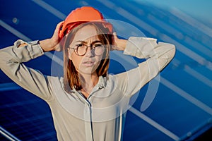 Beautiful young engineer standing near solar panels outdoors, Green Energy Concept