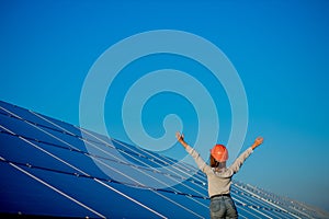 Beautiful young engineer standing near solar panels outdoors, Green Energy Concept