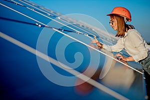 Beautiful young engineer standing near solar panels outdoors, Green Energy Concept