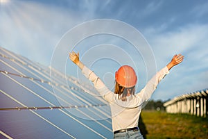 Beautiful young engineer standing near solar panels outdoors, Green Energy Concept