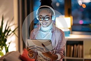 Beautiful young entrepreneur woman using her digital tablet while listening music standing in the office