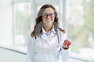 Beautiful young european woman dietologist wearing eyeglasses holding apple