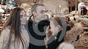 Beautiful young family in an amusement park on against a carousel.