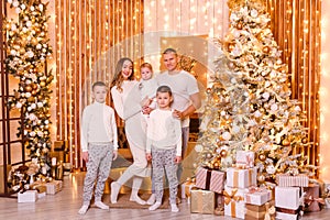 Beautiful young family of five standing near the Christmas tree indoors