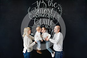 Beautiful young family happy with their kids. The brother kisses little sister.