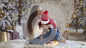 Beautiful young family: mother playing with her baby boy near christmas tree