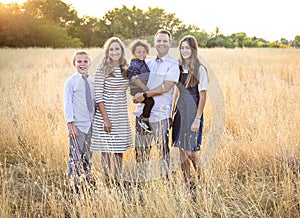 Beautiful young family portrait outdoors in a grassy field