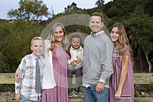 Beautiful young family portrait outdoors in a grassy field