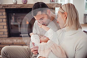 Beautiful young family is reading a book near the fireplace. Cozy