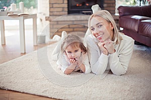 Beautiful young family is reading a book near the fireplace. Cozy