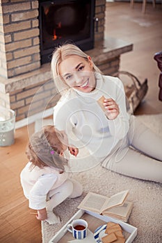 Beautiful young family is reading a book near the fireplace. Cozy