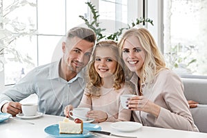 beautiful young family sitting in cafe and looking