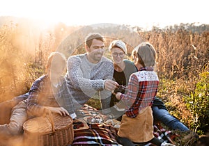Beautiful young family with small children having picnic in autumn nature.