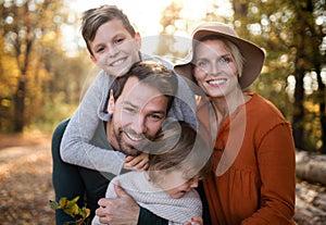 Beautiful young family with small children on a walk in autumn forest.