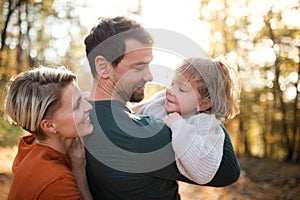 Beautiful young family with small daughter on a walk in autumn forest.