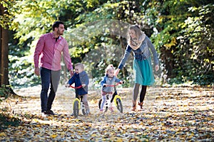 Beautiful young family with small twins on a walk in autumn forest.