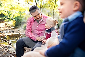 Beautiful young family with small twins on a walk in autumn forest.