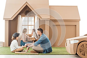 beautiful young family spending time together at cardboard house