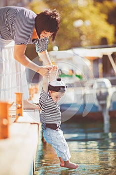 Beautiful young family of two walking along wooden jetty. Woman with son on pier