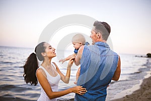 Beautiful young family on vacation with baby. The father holds the blonde girl in her arms, and the brunette`s mother hugs her