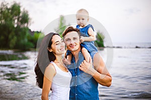 Beautiful young family on vacation with baby. The father holds the blonde girl in her arms, and the brunette`s mother hugs her hu