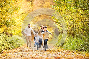 Beautiful young family on a walk in autumn forest.