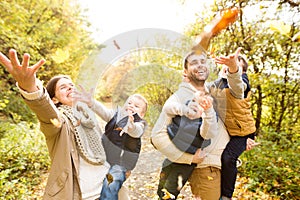 Beautiful young family on a walk in autumn forest.