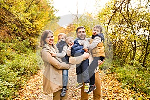 Beautiful young family on a walk in autumn forest.