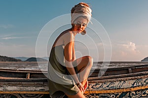 Beautiful young fashion model on the beach at sea boat at sunset