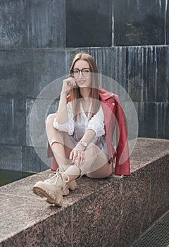 Beautiful young fashion stylish woman sitting on the parapet