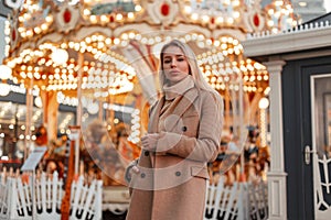 Beautiful young fashion woman in a stylish autumn coat and vintage knitted sweater in an amusement park