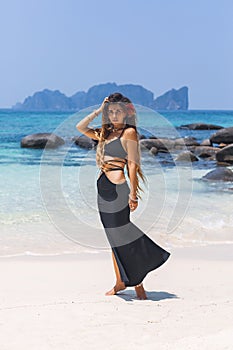 Beautiful young fashionable woman in black dress posing at the beach