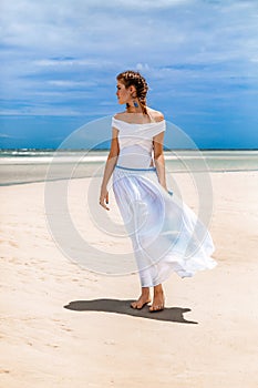 Beautiful young fashionable woman in white dress at the beach