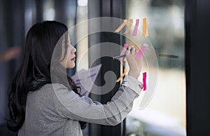 Beautiful young female asian designer writing on sticky notes