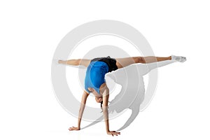 Beautiful young female athlete stretching on white studio background with shadows