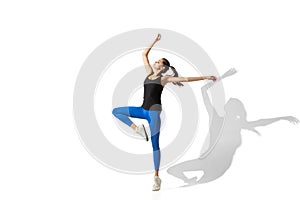 Beautiful young female athlete stretching on white studio background with shadows