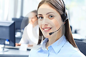 Beautiful young female call center operator with headset in office.