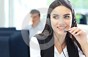 Beautiful young female call center operator with headset in office.