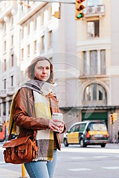 Beautiful young female commuter waiting in the street with a coffee