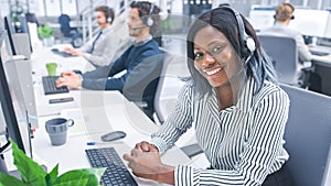 Beautiful Young Female Customer Service Operator Smiling for a Portrait at a Busy Modern Call Center