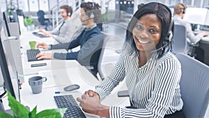 Beautiful Young Female Customer Service Operator Smiling for a Portrait at a Busy Modern Call Center