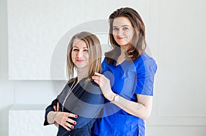 Beautiful young female doctors posing in blue uniforms against white wall background