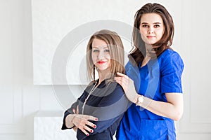 Beautiful young female doctors posing in blue uniforms against white wall background