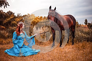 Beautiful young female elf with long dark wavy hair petting her horse resting in the woods forest nymph stroking her horse care