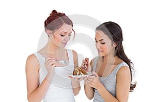Beautiful young female friends pastry cake together