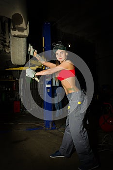 Beautiful young female mechanic inspecting car in auto repair shop. mechanic