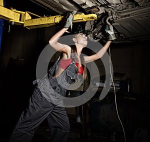 Beautiful young female mechanic inspecting car in auto repair shop. mechanic