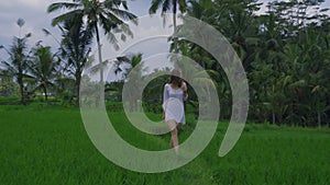 Beautiful young female model in tunic walking along the rice field on Bali with wonderful view