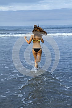 Beautiful young female runs into the ocean surf