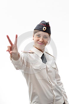 Beautiful young female Russian police officer in dress uniform shows hand signs perfectly and smiles on a white background
